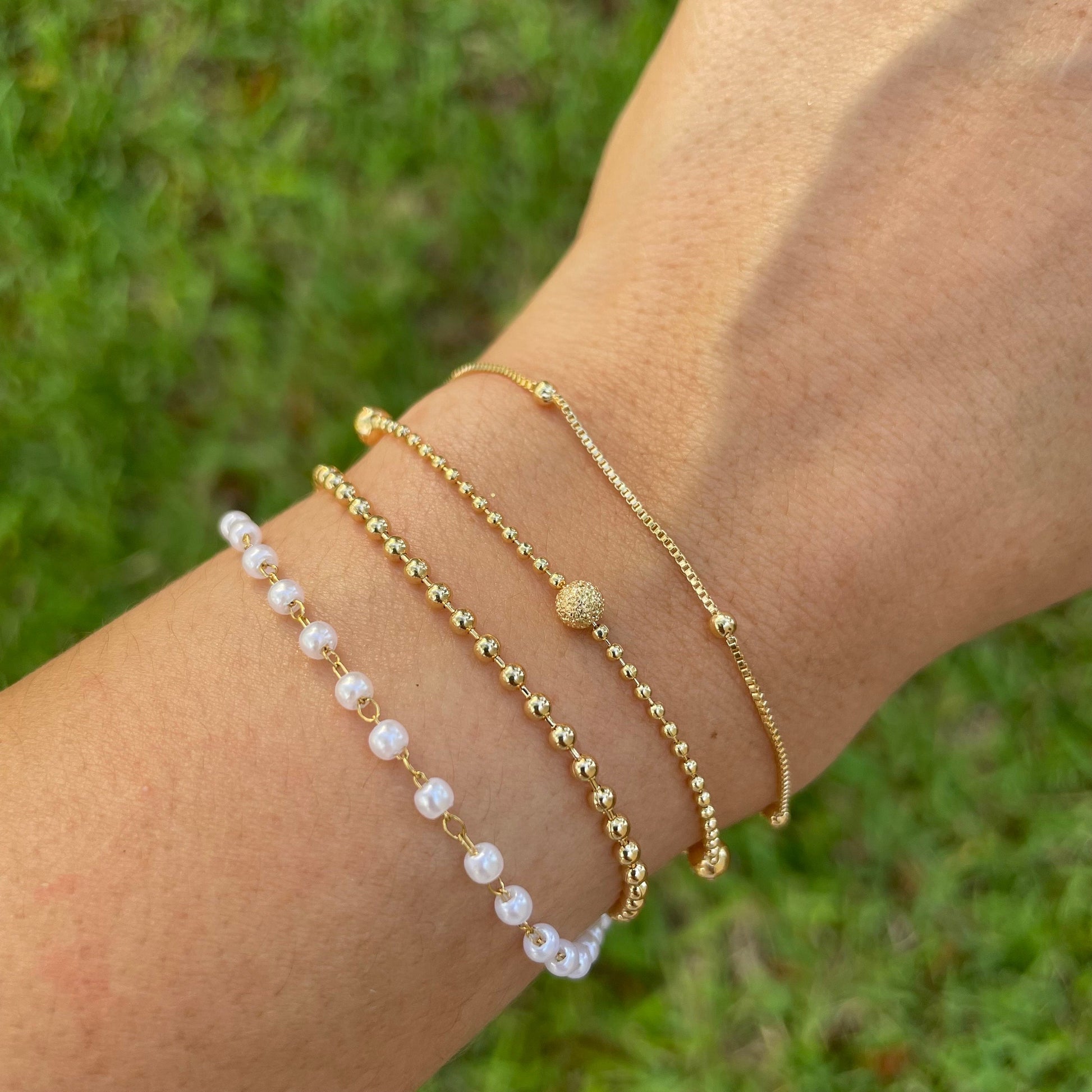 Bracelet stack of 4. 3mm faux pearl bracelet made of stainless steel, 2mm beaded chain made of 18k gold filled, 1mm and 4mm beaded bracelet in 18k gold filled and satellite chain bracelet. Sizes can be customize. Nature background