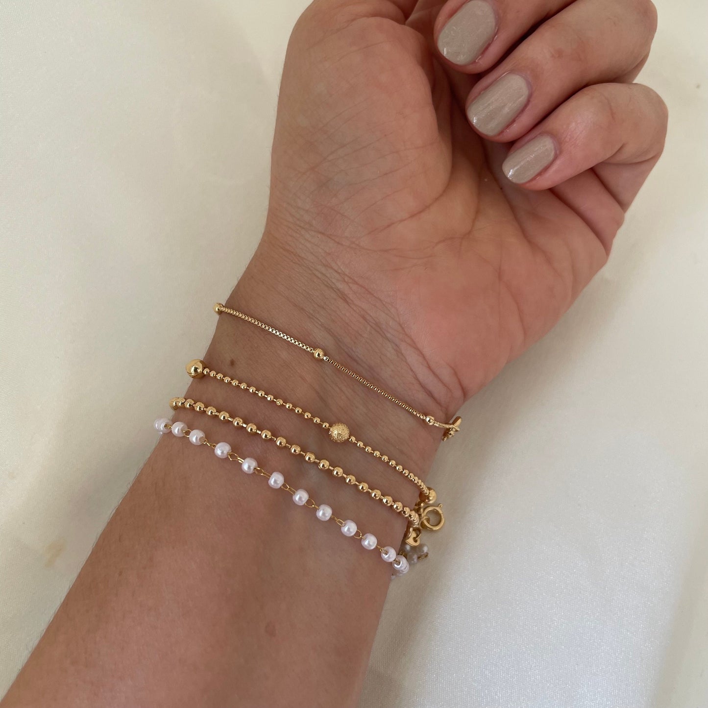 Bracelet stack of 4. 3mm faux pearl bracelet made of stainless steel, 2mm beaded chain made of 18k gold filled, 1mm and 4mm beaded bracelet in 18k gold filled and satellite chain bracelet. Sizes can be customize. Off white background