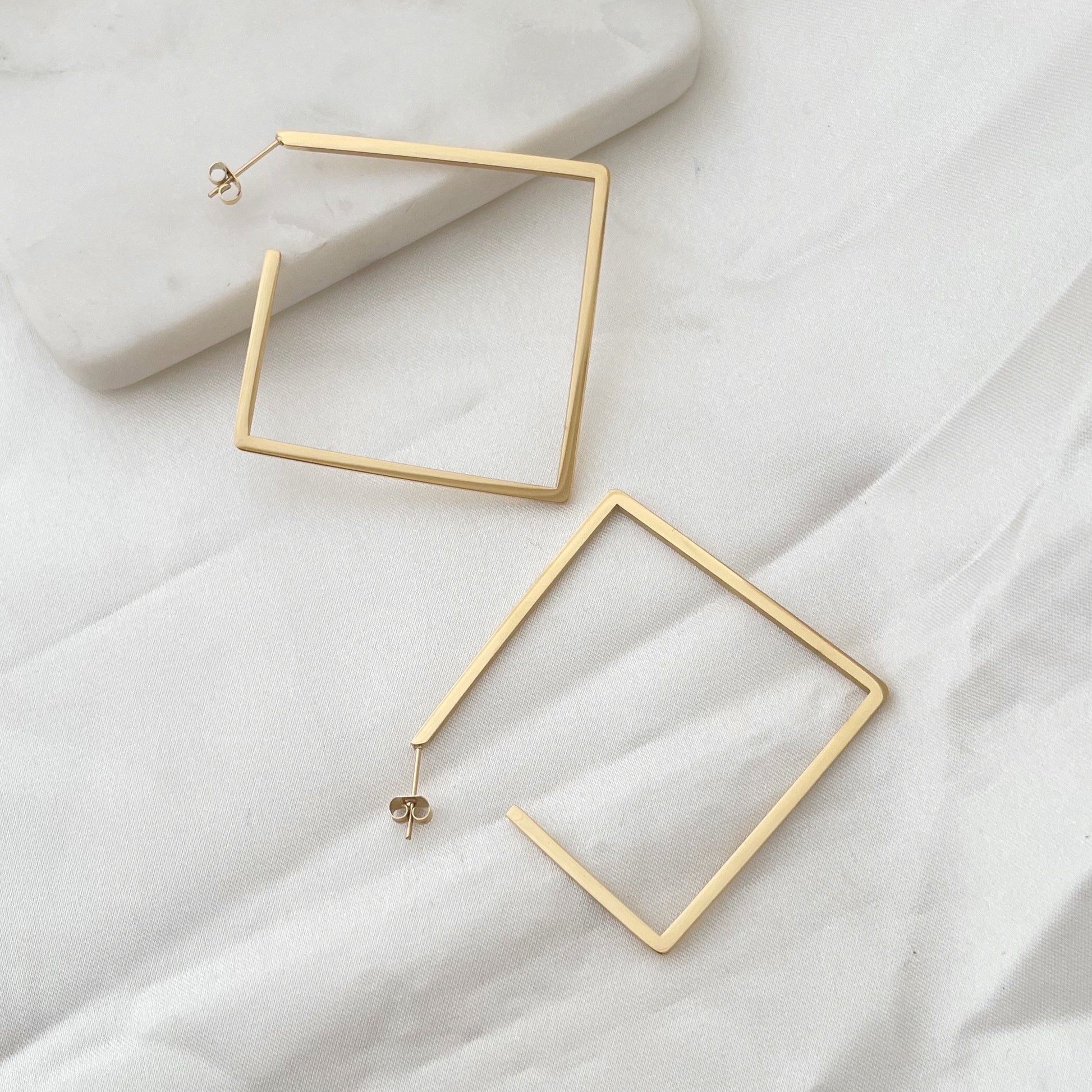 Stainless steel square hoops, 2.5 inches wide, push back hoop earring. Marble tray and white silky background