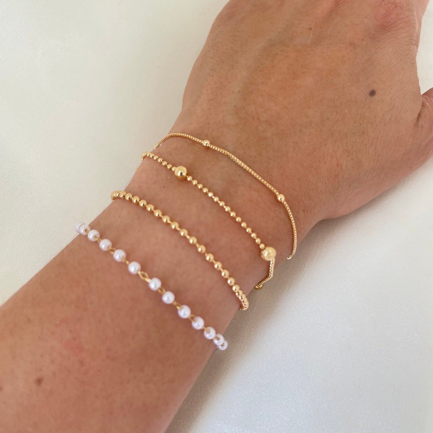 Bracelet stack of 4. 3mm faux pearl bracelet made of stainless steel, 2mm beaded chain made of 18k gold filled, 1mm and 4mm beaded bracelet in 18k gold filled and satellite chain bracelet. Sizes can be customize.