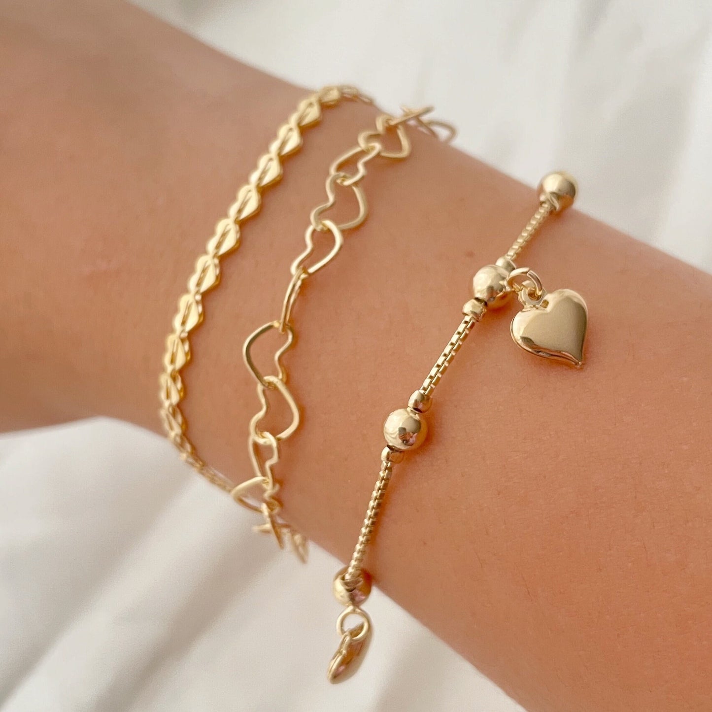 Set of 3 18k gold filled heart bracelets, 3 different styles: full heart bracelet, hollow heart link chain and dangle heart  bracelets. Displayed on arm