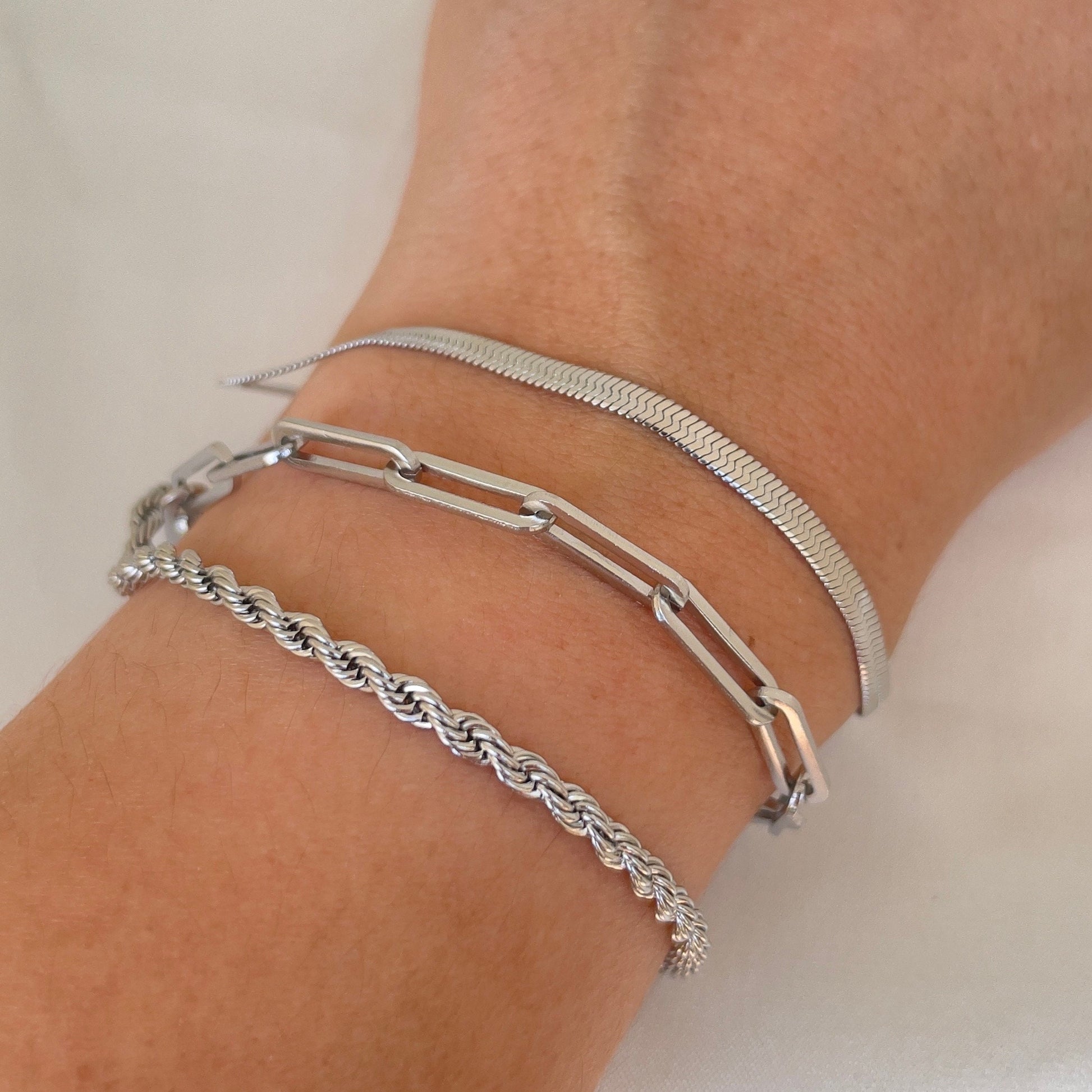 3 stainless steel bracelets displayed on wrist. Thick paperclip bracelet, 4mm herringbone and 4 mm rope bracelet