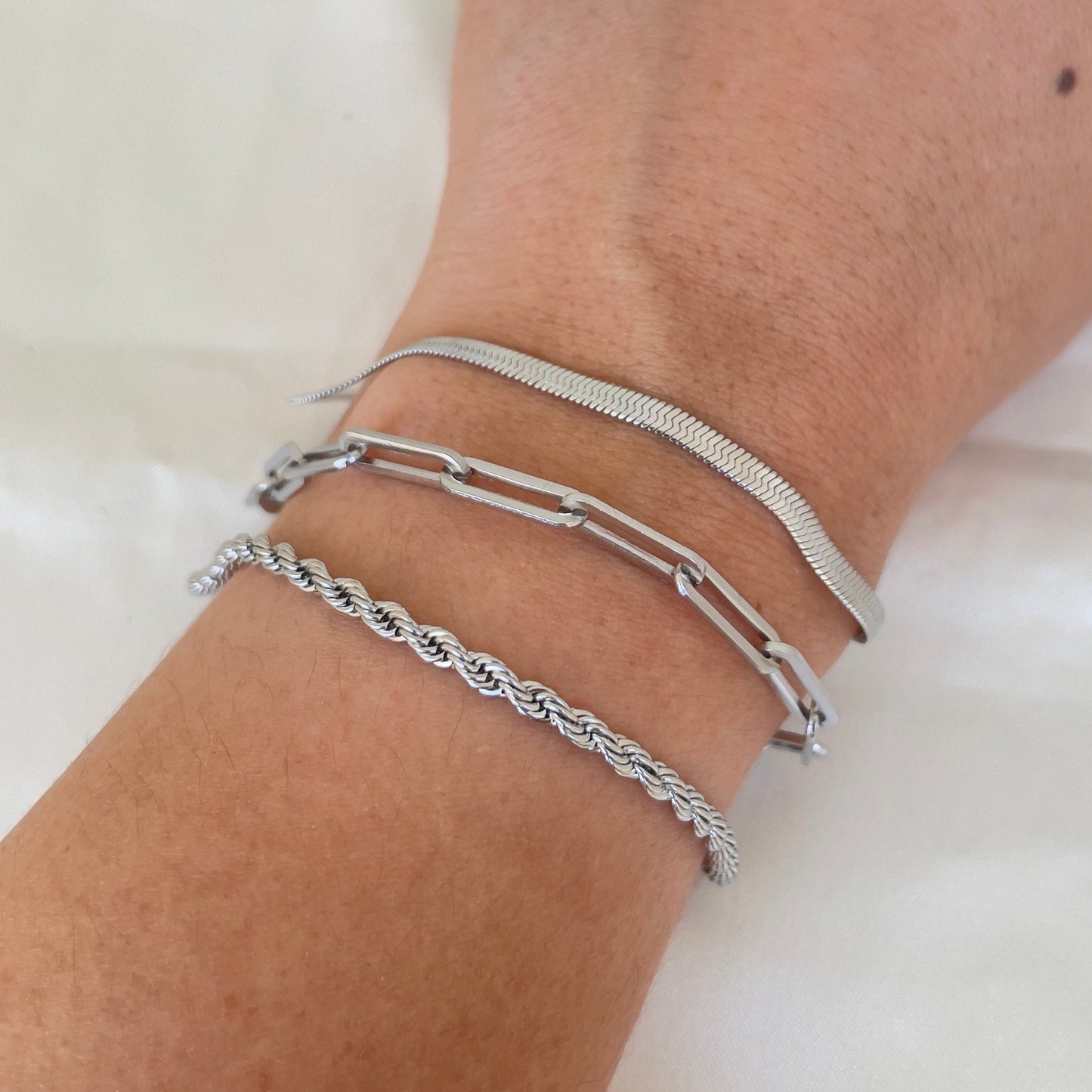 3 stainless steel bracelets displayed on wrist. Thick paperclip bracelet, 4mm herringbone and 4 mm rope bracelet