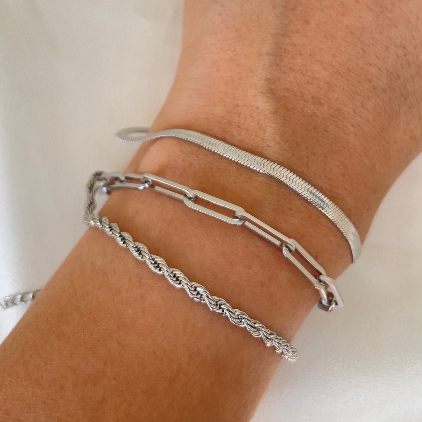 3 stainless steel bracelets displayed on wrist. Thick paperclip bracelet, 4mm herringbone and 4 mm rope bracelet