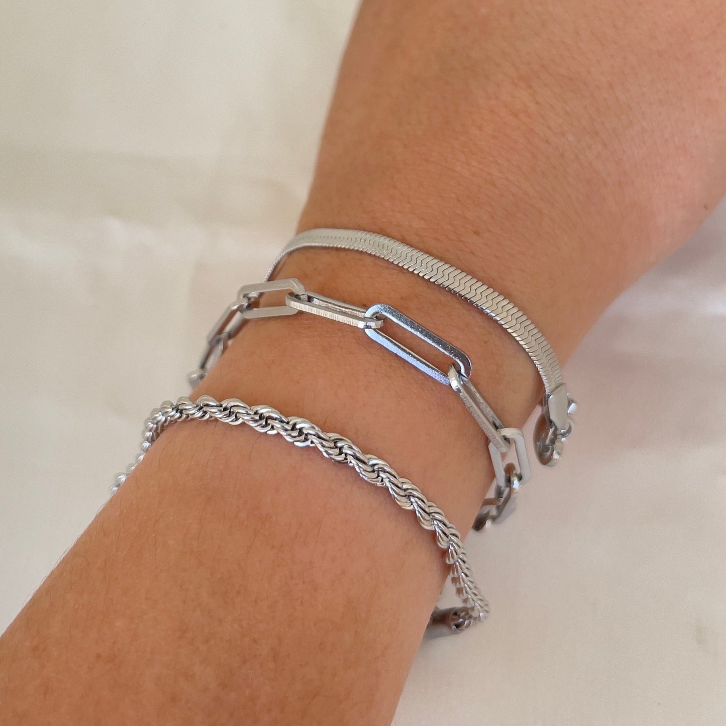 3 stainless steel bracelets displayed on wrist. Thick paperclip bracelet, 4mm herringbone and 4 mm rope bracelet