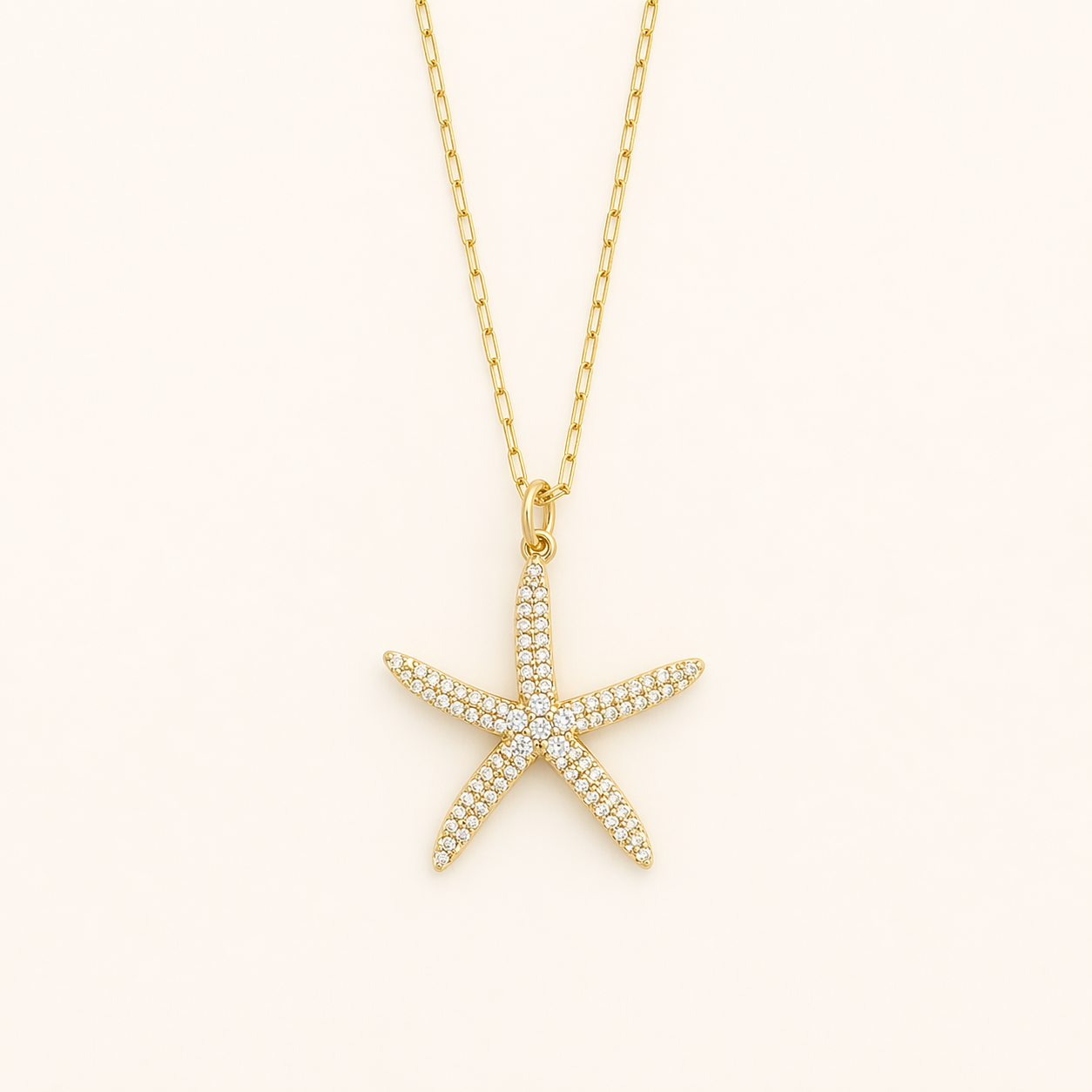 Gold starfish pendant necklace on a light beige background